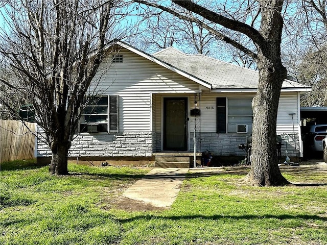 view of front of property featuring stone siding, fence, and a front lawn