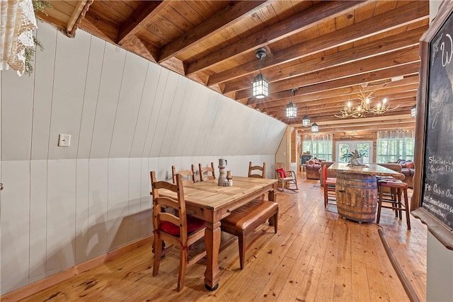 dining room with vaulted ceiling with beams, light wood-type flooring, wood ceiling, and a chandelier