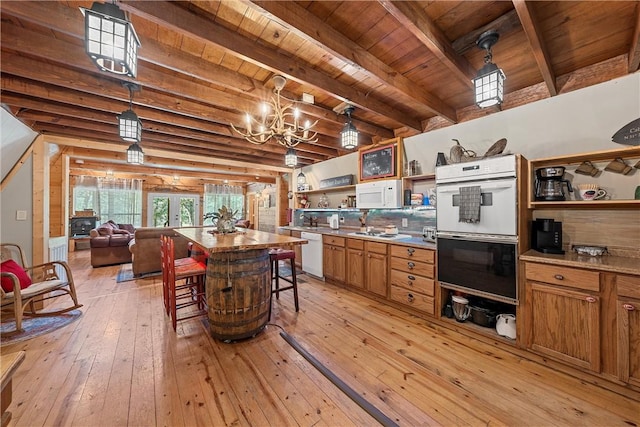 kitchen featuring white appliances, wooden ceiling, hanging light fixtures, light hardwood / wood-style floors, and a breakfast bar area