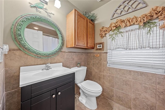 bathroom with tile patterned flooring, vanity, toilet, and tile walls