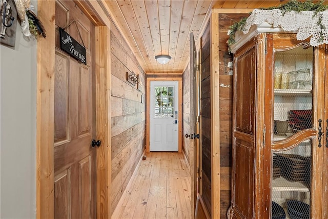 doorway to outside featuring light wood-type flooring, wood ceiling, and wood walls