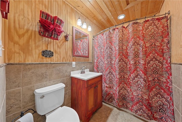 bathroom featuring tile patterned floors, toilet, vanity, wood ceiling, and tile walls