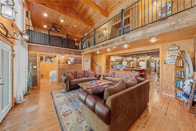 living room with wood walls, high vaulted ceiling, ceiling fan, light wood-type flooring, and wood ceiling