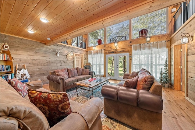 living room featuring french doors, light wood-type flooring, wooden ceiling, and wood walls