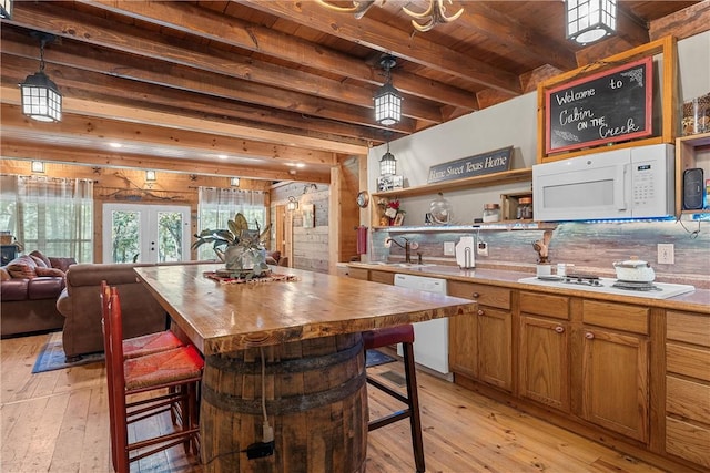 kitchen featuring beam ceiling, light wood-type flooring, white appliances, and a kitchen breakfast bar