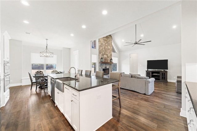 kitchen with white cabinets, sink, a fireplace, and an island with sink