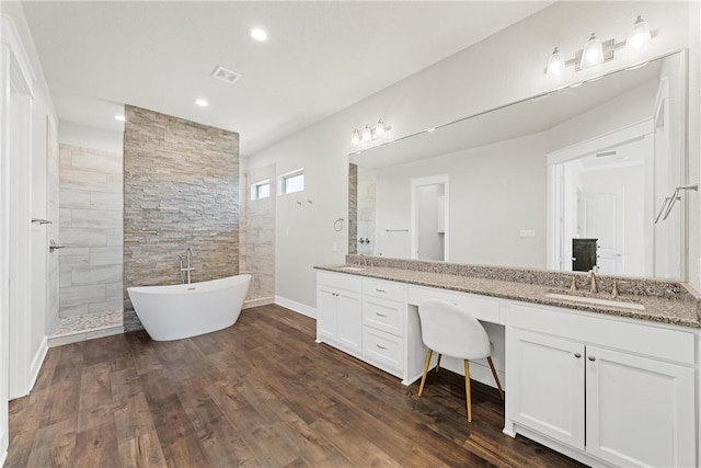 bathroom with plus walk in shower, hardwood / wood-style floors, and vanity