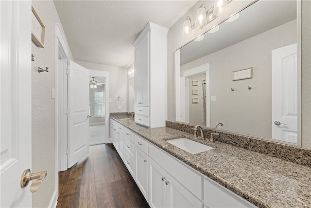 bathroom featuring hardwood / wood-style flooring, vanity, ceiling fan, and a textured ceiling