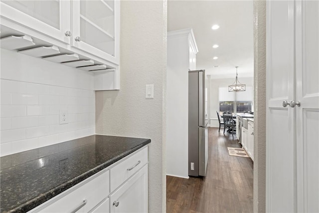 kitchen featuring stainless steel fridge, dark stone counters, white cabinetry, and dark wood-type flooring