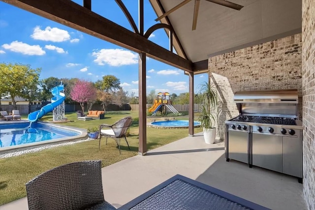 view of patio with a fenced in pool, an outdoor kitchen, and a playground