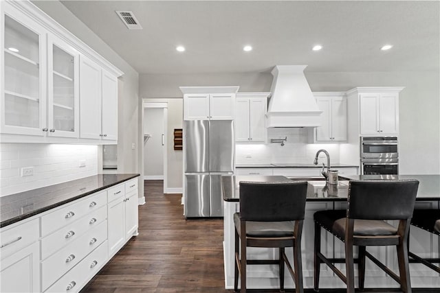 kitchen with white cabinetry, dark hardwood / wood-style flooring, stainless steel appliances, and custom range hood