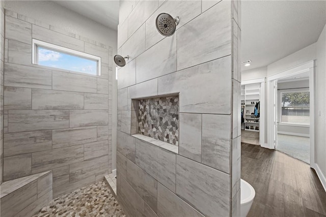 bathroom featuring plenty of natural light, wood-type flooring, and tiled shower