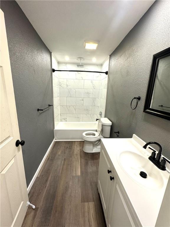 full bathroom featuring tiled shower / bath, vanity, wood-type flooring, and toilet