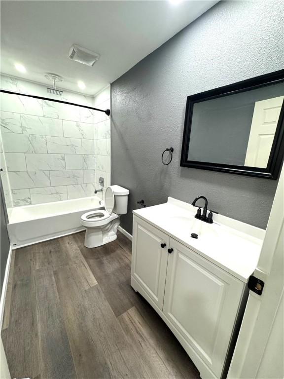 full bathroom with toilet, vanity, hardwood / wood-style flooring, and tiled shower / bath combo