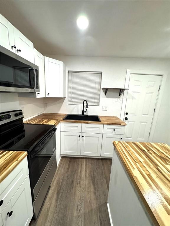 kitchen featuring sink, white cabinets, wooden counters, and appliances with stainless steel finishes