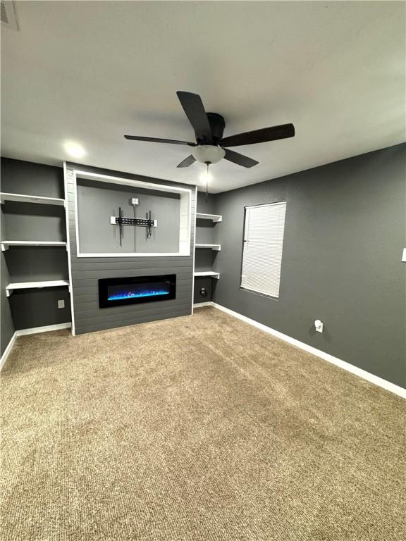 unfurnished living room with carpet flooring, ceiling fan, and a large fireplace