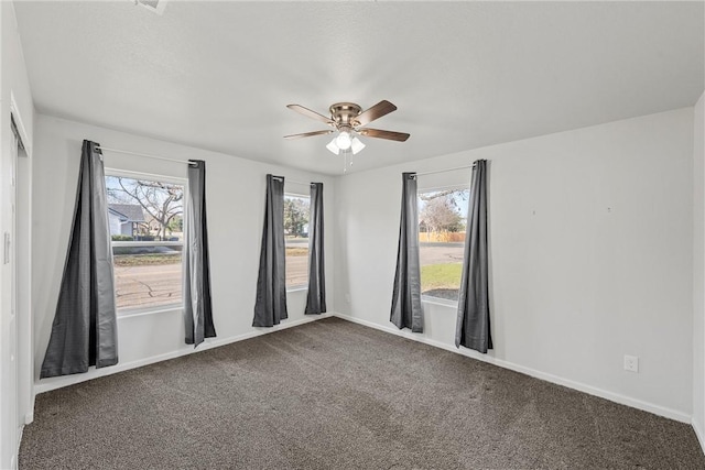 carpeted spare room featuring ceiling fan and plenty of natural light