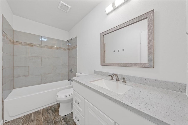 full bathroom featuring toilet, vanity, and tiled shower / bath