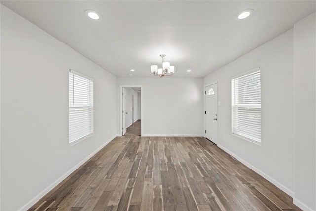 spare room with a healthy amount of sunlight, hardwood / wood-style floors, and a chandelier