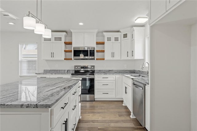 kitchen featuring stainless steel appliances, decorative light fixtures, white cabinetry, and sink