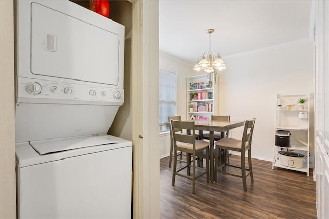 laundry area featuring an inviting chandelier, ornamental molding, stacked washer and clothes dryer, and dark hardwood / wood-style floors