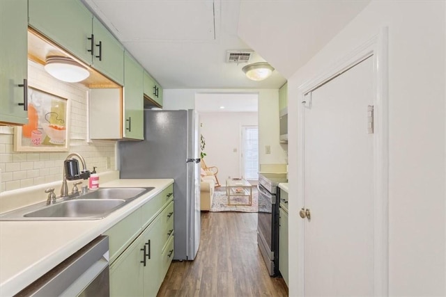 kitchen featuring sink, decorative backsplash, green cabinetry, and appliances with stainless steel finishes