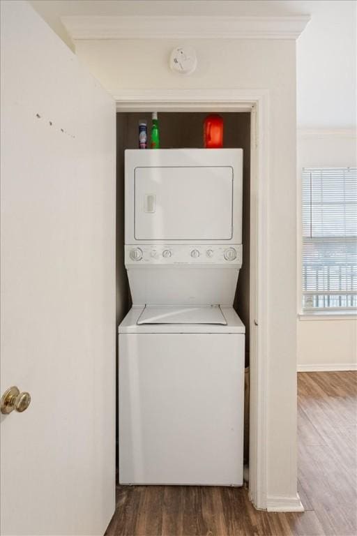 washroom with stacked washer and dryer, ornamental molding, and dark hardwood / wood-style flooring