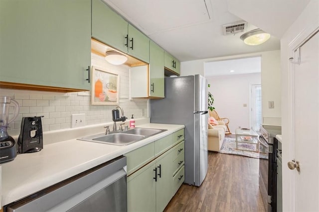 kitchen with sink, decorative backsplash, green cabinets, stainless steel appliances, and dark wood-type flooring