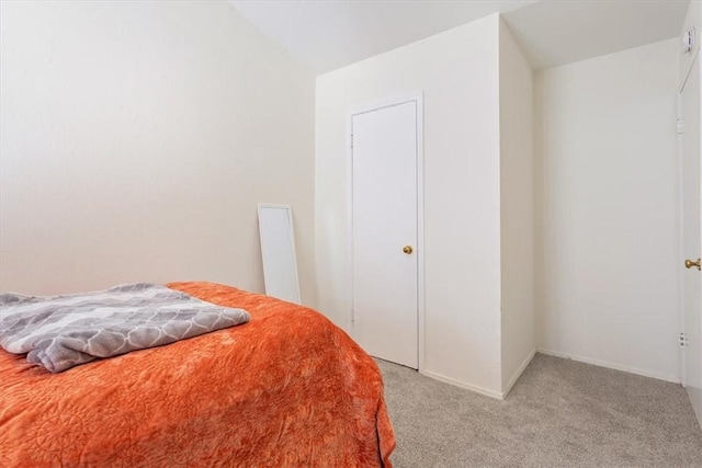 bedroom with light colored carpet and lofted ceiling