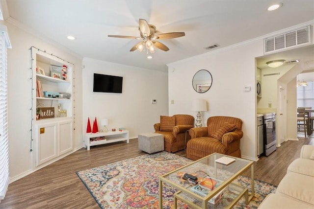 living room featuring dark hardwood / wood-style flooring, crown molding, and ceiling fan