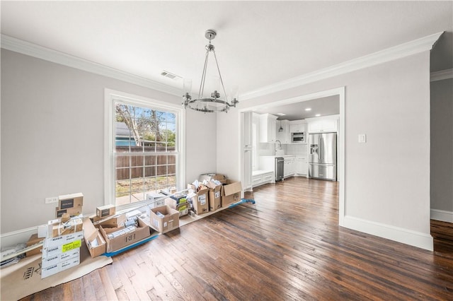 unfurnished dining area featuring ornamental molding, sink, dark wood-type flooring, and a notable chandelier