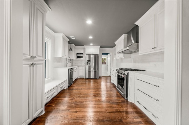 kitchen featuring tasteful backsplash, stainless steel appliances, wall chimney range hood, white cabinets, and dark hardwood / wood-style floors