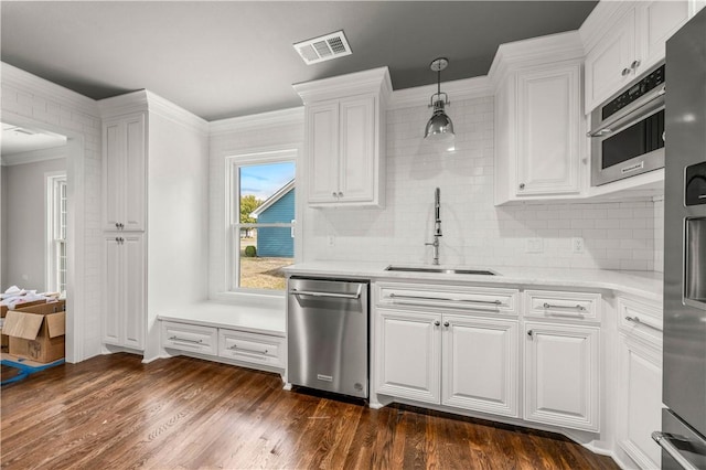 kitchen featuring white cabinetry, sink, dark hardwood / wood-style floors, pendant lighting, and ornamental molding