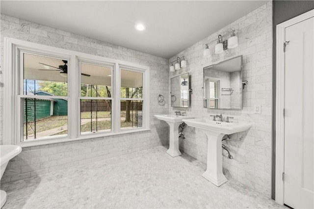 bathroom featuring ceiling fan, a healthy amount of sunlight, and tile walls