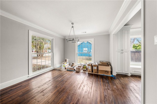 dining room featuring dark hardwood / wood-style floors, crown molding, a healthy amount of sunlight, and a notable chandelier