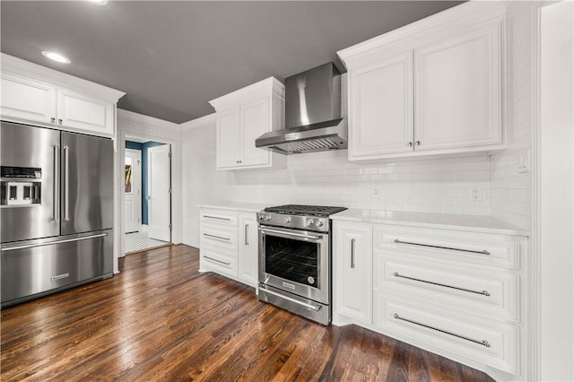 kitchen with dark hardwood / wood-style flooring, white cabinetry, wall chimney exhaust hood, and high quality appliances