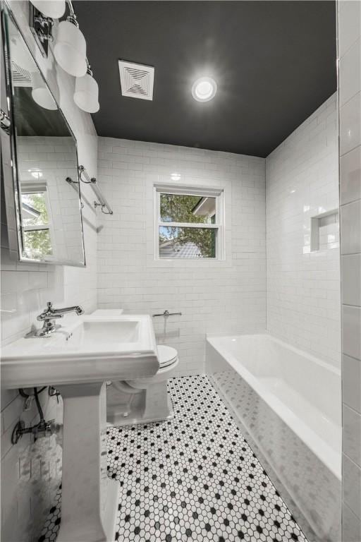 bathroom with tile patterned floors, a healthy amount of sunlight, toilet, and tile walls