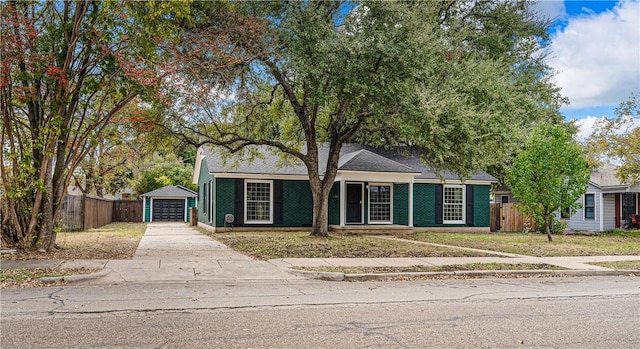 view of front of house featuring a garage, an outbuilding, and a front lawn