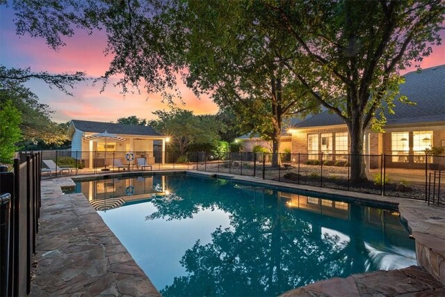 pool at dusk featuring a patio