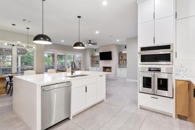 kitchen featuring ceiling fan, sink, stainless steel appliances, a kitchen island with sink, and white cabinets