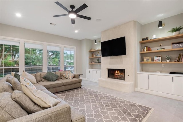 living room featuring ceiling fan, built in features, and a fireplace