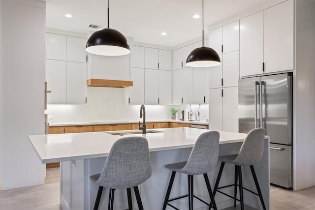 kitchen featuring white cabinets, high end fridge, and hanging light fixtures