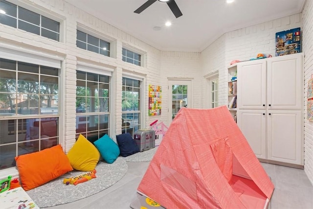 bedroom with ceiling fan and brick wall