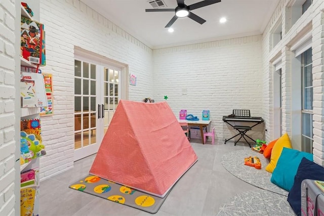 playroom with french doors, ceiling fan, and brick wall