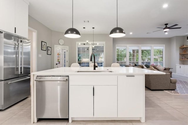 kitchen featuring white cabinetry, sink, stainless steel appliances, and decorative light fixtures