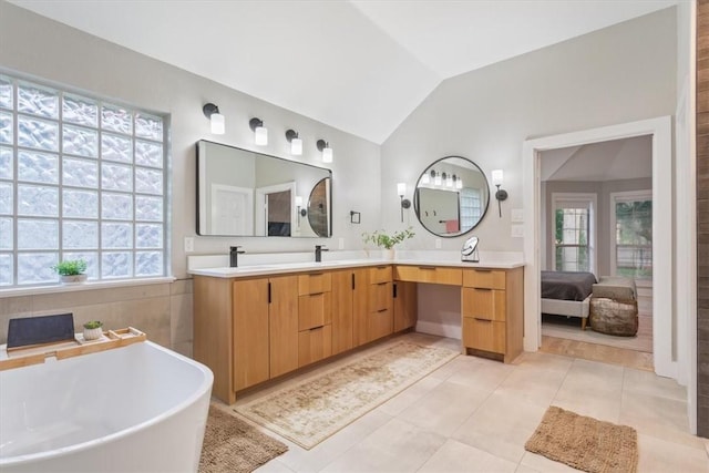 bathroom with tile patterned floors, vanity, a tub to relax in, and vaulted ceiling