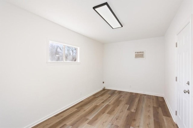 unfurnished room featuring a wall unit AC and light hardwood / wood-style floors