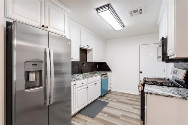 kitchen featuring appliances with stainless steel finishes, white cabinets, sink, and light stone countertops