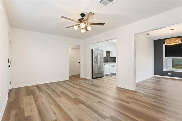 unfurnished living room with ceiling fan, light wood-type flooring, and sink