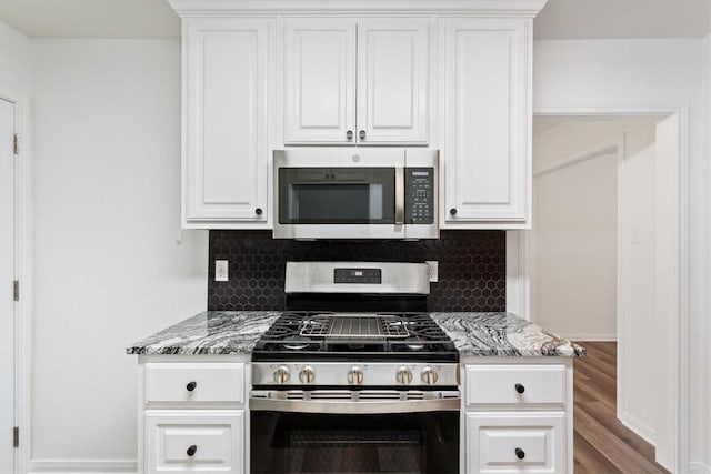 kitchen with decorative backsplash, white cabinetry, light stone counters, and appliances with stainless steel finishes